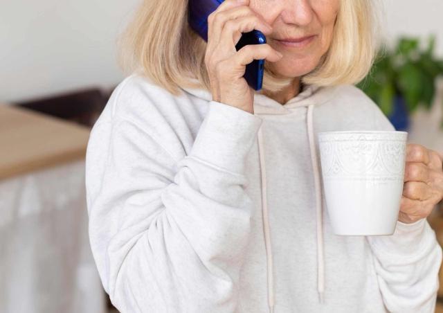 woman holding phone and cup of coffee