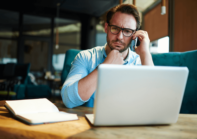 Man on phone looking at laptop